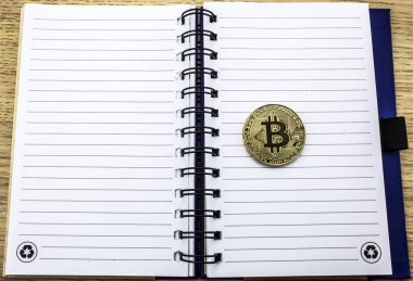 Cryptocurrency fiziksel altın bitcoin. Defter arka plan üzerinde altın bitcoin. 3D çizim.