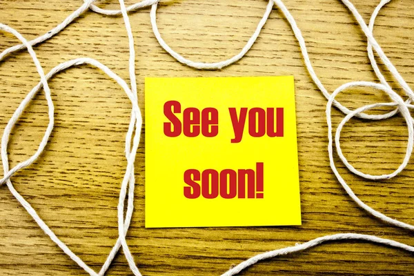 See you soon - word on yellow sticky note in wooden background. Bussines concept.