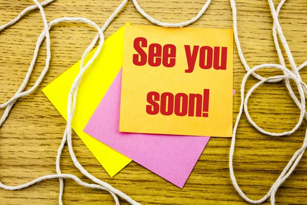 See you soon - word on yellow sticky note in wooden background. Bussines concept.