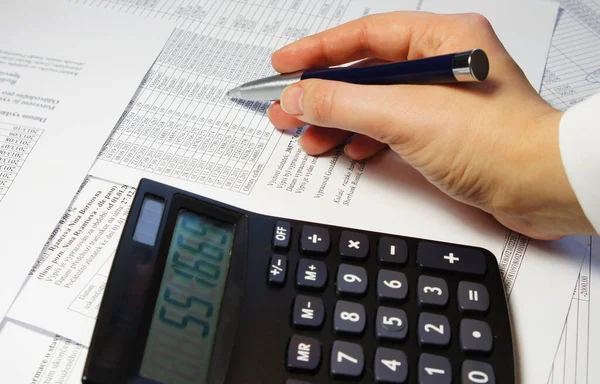 Calculator, pen and accounting document with a lot of numbers and woman hands