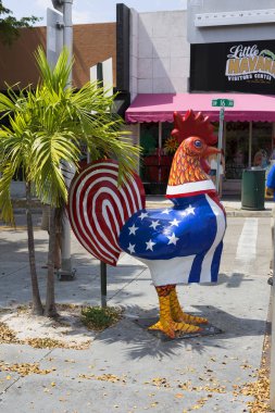Miami, ABD, 03/18/2016, küçük Havana'da. Horoz. Çiçekler küçük Havana'da Küba ve Amerikan bayrağı ile sembolik horoz heykel.