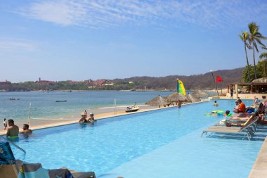 Huatulco, Meksika, 03/06/2016, turist otel Huatulco adlı. Huatulco Bay muhteşem Dağları, yamaçlar, vadiler ve bol bitki örtüsü, muhteşem plajları ile pitoresk bir cennettir. Turistler Huatulco otel havuzunda yüzmek.
