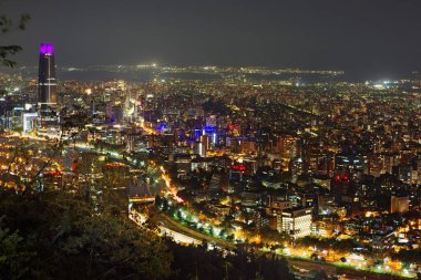 Santiago, Şili, 02 / 15 / 2020, San Cristobal tepesinden gün batımında şehir manzarası. Gün batımının saati, güneş ışığı ile şehri nazikçe okşadığında. Solda, görüntü Gran Torre Santiago 'yu gösteriyor, Santiago' da 64 katlı bir gökdelen.