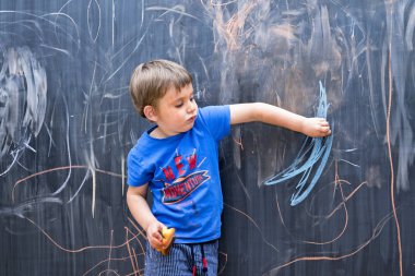Güzel çocuk genç sanatçı bir yazı tahtası üzerinde çizim