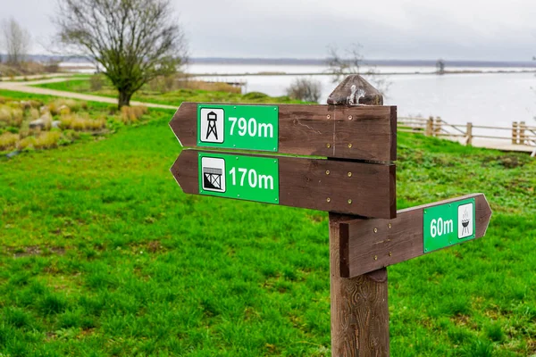 Wooden direction indicator in the park with pictograms and distance signs — Stock Photo, Image