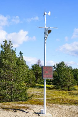 Gökyüzünün altında bilgi panosu olan güneş ve rüzgar enerjisi lambası