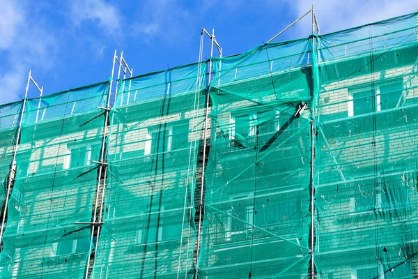 green safety net on scaffolding at the facade of an apartment house under renovation