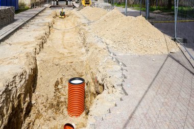 Şehir caddesindeki iletişimin değiştirilmesi, kum çukurundaki yeni turuncu plastik borunun dikey sonu.