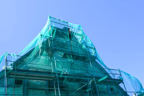 green safety net on scaffolding in the restoration of a historic wooden house