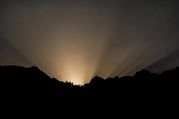 brown sun rays from mountain silhouette
