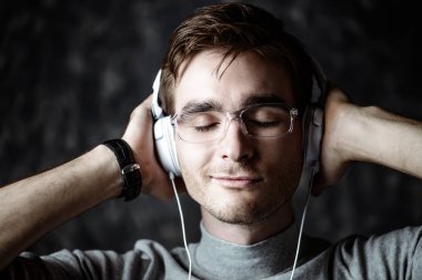 Yakışıklı delikanlı listenig kulaklık ve gülümseyen müzik.
