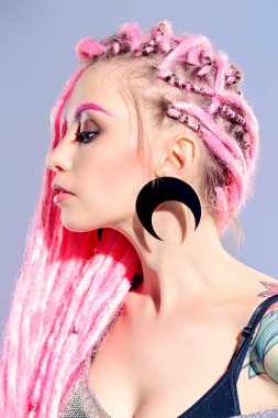 Kadın modeli pembe dreadlocks gri bir arka plan üzerinde poz ile çarpıcı. Son moda saç modelleri. Güzellik, moda. 