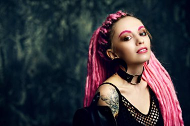 Kadın modeli pembe dreadlocks karanlık bir arka plan üzerinde poz ile çarpıcı. Son moda saç modelleri. Güzellik, moda. 