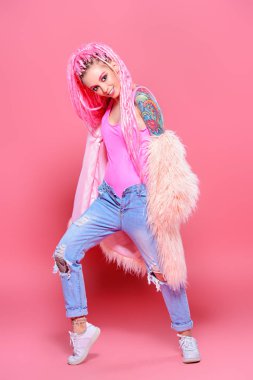 Şık kız pembe dreadlocks pembe bir arka plan üzerinde parlak giysiler içinde poz ile. Tam uzunlukta portre. Güzellik, moda.