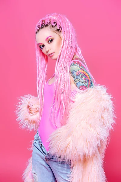 Şık kız pembe dreadlocks pembe bir arka plan üzerinde parlak giysiler içinde poz ile. Güzellik, moda.