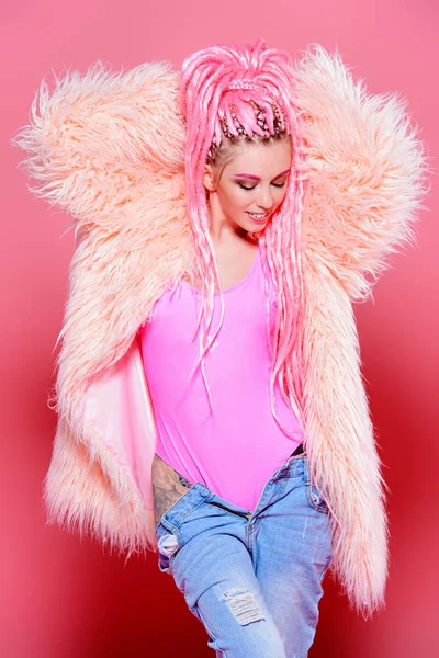 Şık kız pembe dreadlocks pembe bir arka plan üzerinde parlak giysiler içinde poz ile. Güzellik, moda.