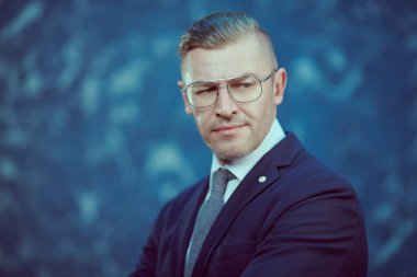 Patron takım elbiseli ve güneş gözlüklü.