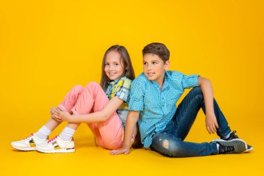 Sarı arka plan üzerinde iki neşeli genç çocukların tam uzunlukta bir portre. Yaz rahat çocuk moda.