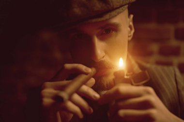 Karanlıkta dalgın dalgın oturup puro içen yakışıklı bir adamın portresi. Lüks bir yaşam tarzı. Retro tarzı. Mafya ve suç dünyası, dedektif..