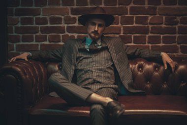 Yakışıklı, kendine güvenen bir adam deri koltukta rahat bir şekilde oturuyor. Lüks bir yaşam tarzı. Retro tarzı. Mafya ve suç dünyası. 