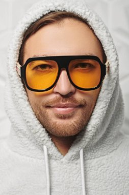 Beyaz kapüşonlu ve şık sarı güneş gözlüklü genç bir adamın portresi. Gençlik tarzı, erkek tarzı..