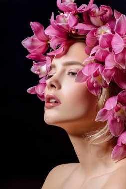 Yakın çekim çiçek çelenk şehvetli bahar kadın portresi. Siyah arka plan. Güzellik, kozmetik. Kalıcı makyaj.