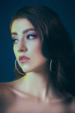 Güzel kadın. Koyu renk saçlı ve koyu mavi arka planda zarif mor makyajlı zarif bir genç kadının portresi. Makyaj ve makyaj malzemeleri. Mükemmel cilt.