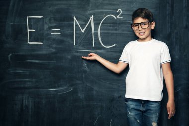 Sınıftaki tahtanın üzerinde gülen genç bir öğrencinin portresi. Güzellik, moda, okul, eğitim.