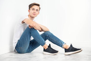 Beyaz tişörtlü genç, yakışıklı bir adamın portresi. Erkeklerin güzelliği, gündelik moda.