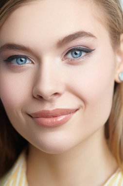 Kameraya gülümseyen doğal makyajlı mutlu bir genç kızın portresi. Stüdyo güzellik portresi.