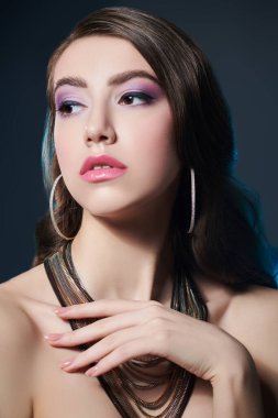 Güzellik, moda ve mücevher. Koyu bir arka planda uzun dalgalı saçlarla poz veren muhteşem bir genç kadının portresi. Mücevher salonu..