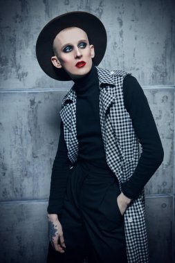 Kadın makyajlı solgun bir gencin portresi ve siyah bir arka planda kırmızı mücevherli taç.. 