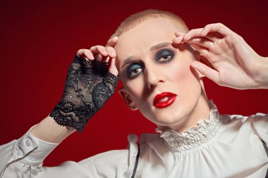 Kadın makyajlı solgun bir gencin portresi ve siyah bir arka planda kırmızı mücevherli taç.. 