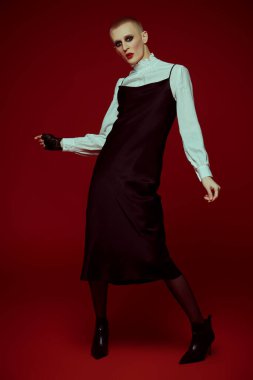 Kadın makyajlı, siyah arka planda kulaklarında değerli küpeleri olan çıplak bir genç adamın portresi.. 