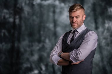 Stüdyoya poz veren yakışıklı acımasız olgun bir adamın portresi. Gündelik resmi moda, erkek güzelliği.