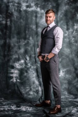 Stüdyoda poz veren yakışıklı, vahşi olgun bir adamın tam uzunlukta bir portresi. Erkekler için casual resmi moda.