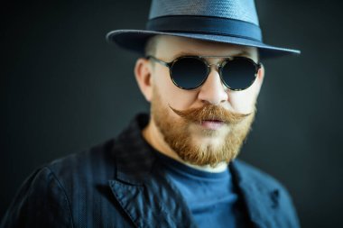 Siyah arka plan üzerinde stüdyoda poz güneş gözlüğü şık bir adam bir yakın yukarı portre. Erkek güzelliği, moda, stil, optik.