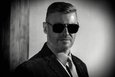 Güneş gözlüklü yakışıklı bir adamın siyah beyaz portresi. Erkek güzelliği, moda. Erkekler için optik.