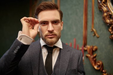 Yakışıklı beyefendi tüvit takım elbise içinde poz veriyor ve gözlük takıyor. Lüks bir yaşam tarzı. Klasik stil. 