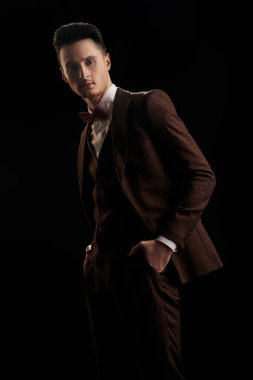 Siyah arka planda zarif bir takım elbise ve papyon giymiş yakışıklı bir adamın portresi. İş stili. Erkek modası.