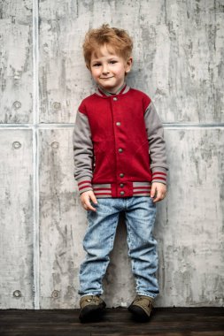 Stüdyoda gri arka planda poz veren mutlu bir gencin uzun bir portresi. Çocuklar günlük moda, eğitim.