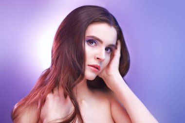 Açık renk leylak, mor makyaj ve uzun saçlı güzel bir kadın. Sağlık, spa ve vücut bakımı. Makyaj ve makyaj malzemeleri. Saç bakımı.