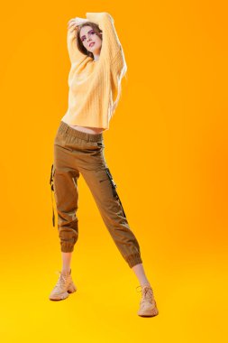 Full length portrait of a pretty young girl with bright pink make-up on a yellow background. Copy space.