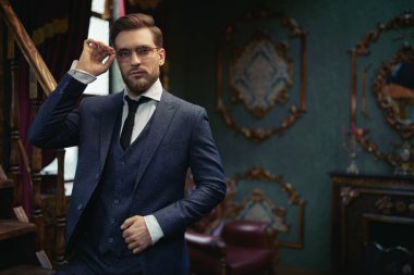 Yakışıklı beyefendi tüvit takım elbise içinde poz veriyor ve gözlük takıyor. Lüks bir yaşam tarzı. Klasik stil. 