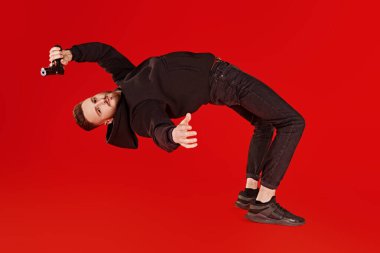 Siyah elbiseli yakışıklı bir adam silahlı uçuyor. Süper ajan görevde. Suç dünyası, anti terörizm. Kırmızı arkaplanda stüdyo çekimi.