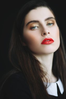 Siyah arka plan üzerinde poz veren koyu saçlı genç bir kadının yakın bir portresi. Güzellik, kozmetik, moda.