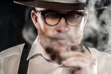 Puro içen bir adamın yakın plan portresi. Erkek güzelliği, moda, tarz.