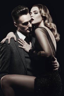 Siyah arka planda pahalı gece elbiseleri giyen güzel tutkulu bir çift. Birbirine aşık bir çift. Güzellik, moda. Stüdyo resmi.