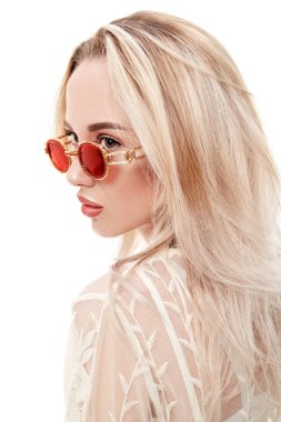 Yaz stili. Açık beyaz dantelli elbise ve güneş gözlüğü takan sarışın güzel bir kızın portresi. Beyaz arkaplanda stüdyo portresi.