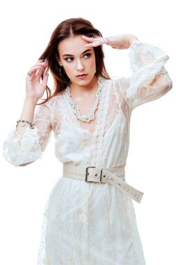 Güzellik portresi. Beyaz arka planda beyaz dantel elbise giyen doğal makyajlı zarif bir genç kadın. Yaz modası. 